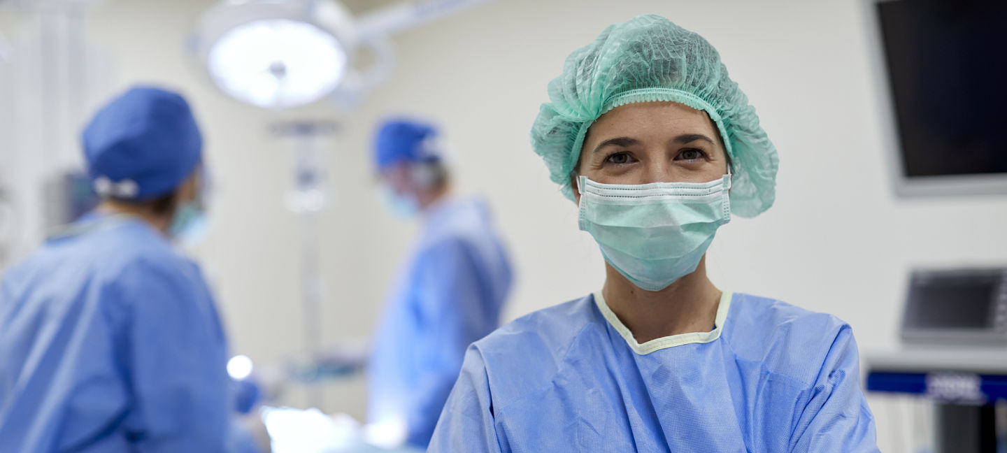 One female surgeon wearing a protective mask and looking at camera